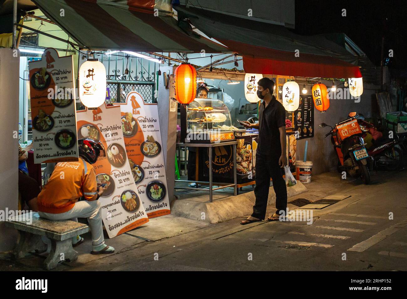 Bangkok, Thailandia - 20 gennaio 2023: Persone di fronte a un venditore di generi alimentari per strada a Bangkok, Thailandia. Foto Stock
