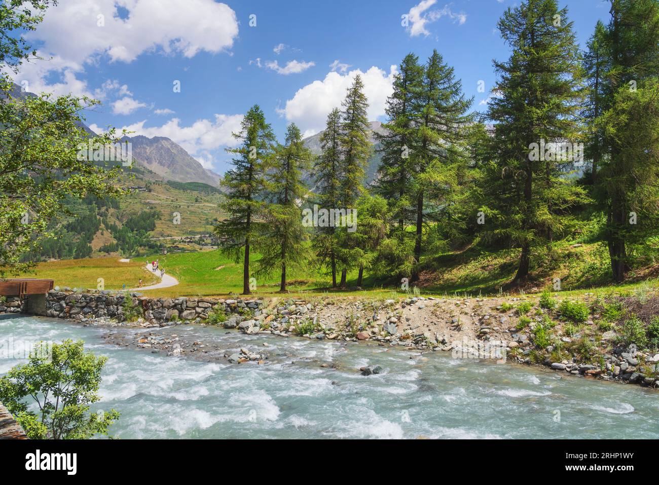 Paesaggio montano estivo a Prati di Sant'Orso, Alpi italiane. Un torrente, alberi e un sentiero. Cogne, Valle d'Aosta, Italia Foto Stock
