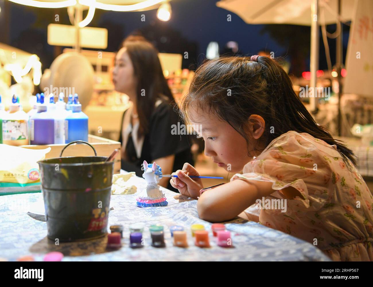 (230818) -- PECHINO, 18 agosto 2023 (Xinhua) -- Un bambino dipinge una bambola in gesso in un mercato notturno nel distretto di Jiangbei, Chongqing della Cina sud-occidentale, 4 agosto 2023. Chongqing, una città sul fiume Yangtze, è chiamata "stufa" dai cinesi a causa della sua alta temperatura estiva; il Cairo, situato sulle rive del Nilo, è stato a lungo un luogo caldo ai margini del deserto. Entrambe le città hanno promosso vigorosamente l'economia notturna. Hongyadong a Chongqing è un'antica porta della città che è stata trasformata in un gigantesco edificio sospeso con ristoranti e altri luoghi di intrattenimento. Kha Foto Stock