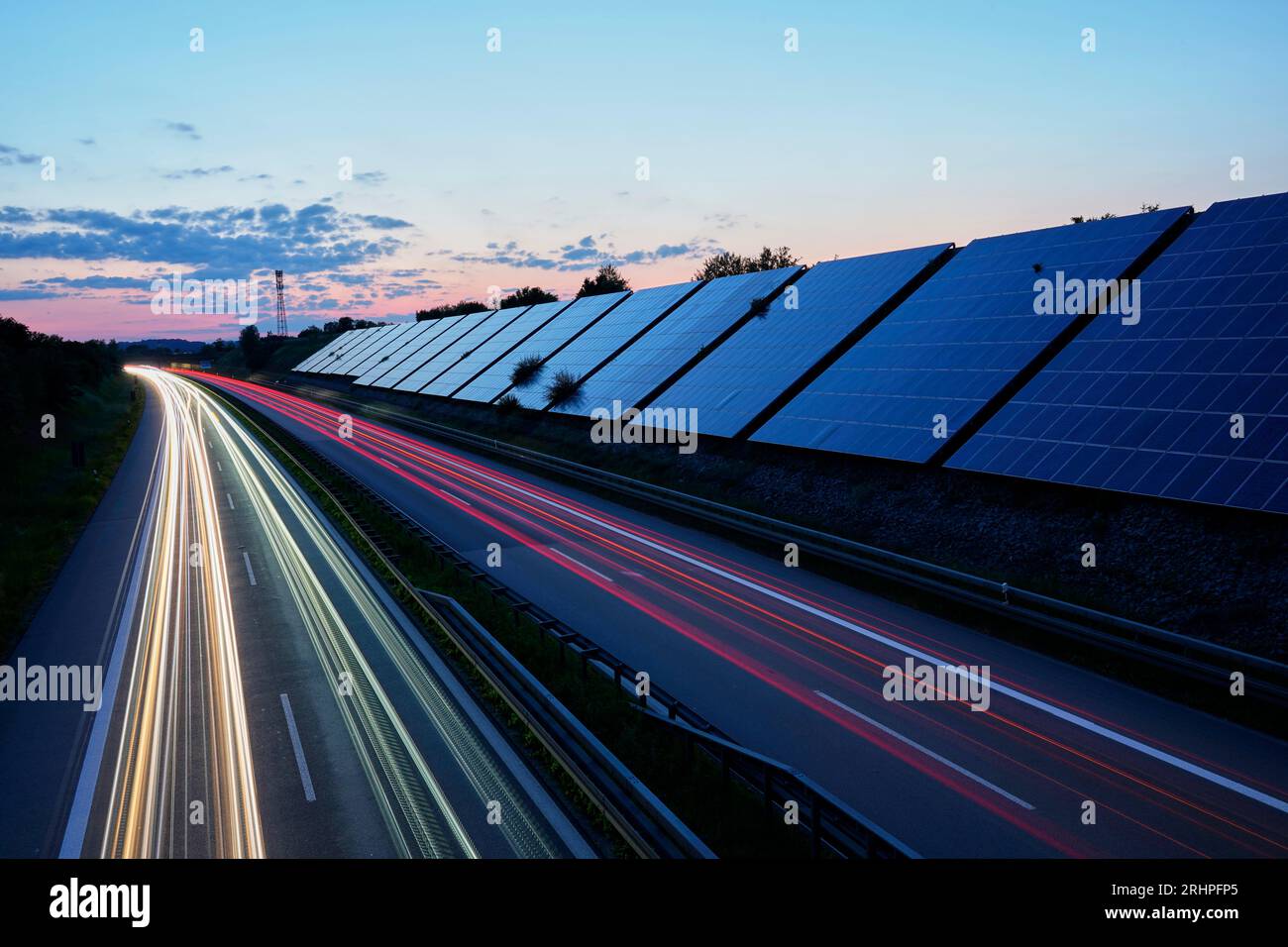 Germania, Baviera, alta Baviera, distretto di Altötting, A94, impianto fotovoltaico sul terrapieno lungo l'autostrada, sera, ora blu, striscia luminosa di traffico in movimento Foto Stock