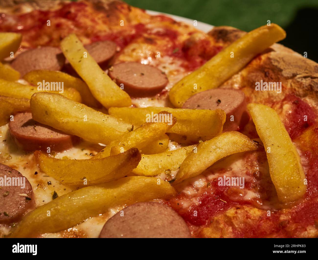 Una pizza condita con patatine fritte e fette di hot dog, chiamata umoristicamente "pizza americana", servita a Cuneo, Piemonte, Italia Foto Stock
