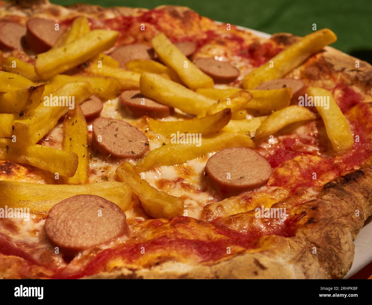 Una pizza condita con patatine fritte e fette di hot dog, chiamata umoristicamente "pizza americana", servita a Cuneo, Piemonte, Italia Foto Stock