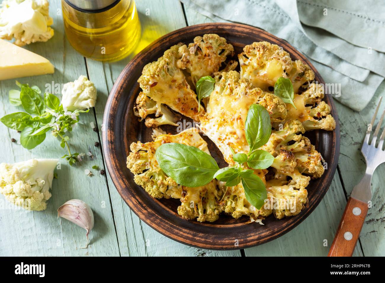 Alimentazione sana, base vegetale carne sostituto concetto.vegetariano cibo biologico. Bistecche di cavolfiore al forno con erbe e spezie su un tavolo di legno. Foto Stock