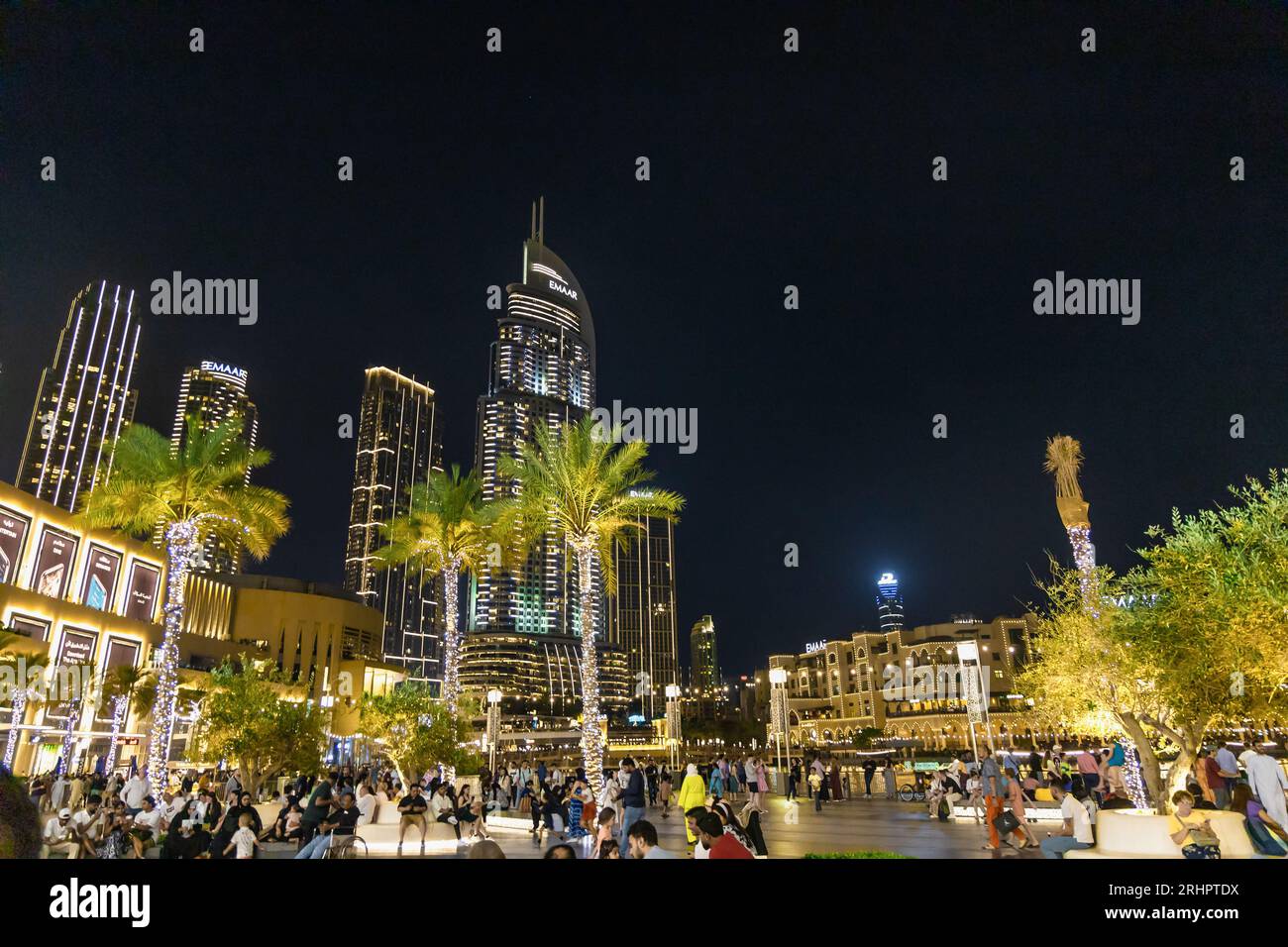 Dubai Street in serata con gente, alti edifici e palme. Dubai, Emirati Arabi Uniti Foto Stock