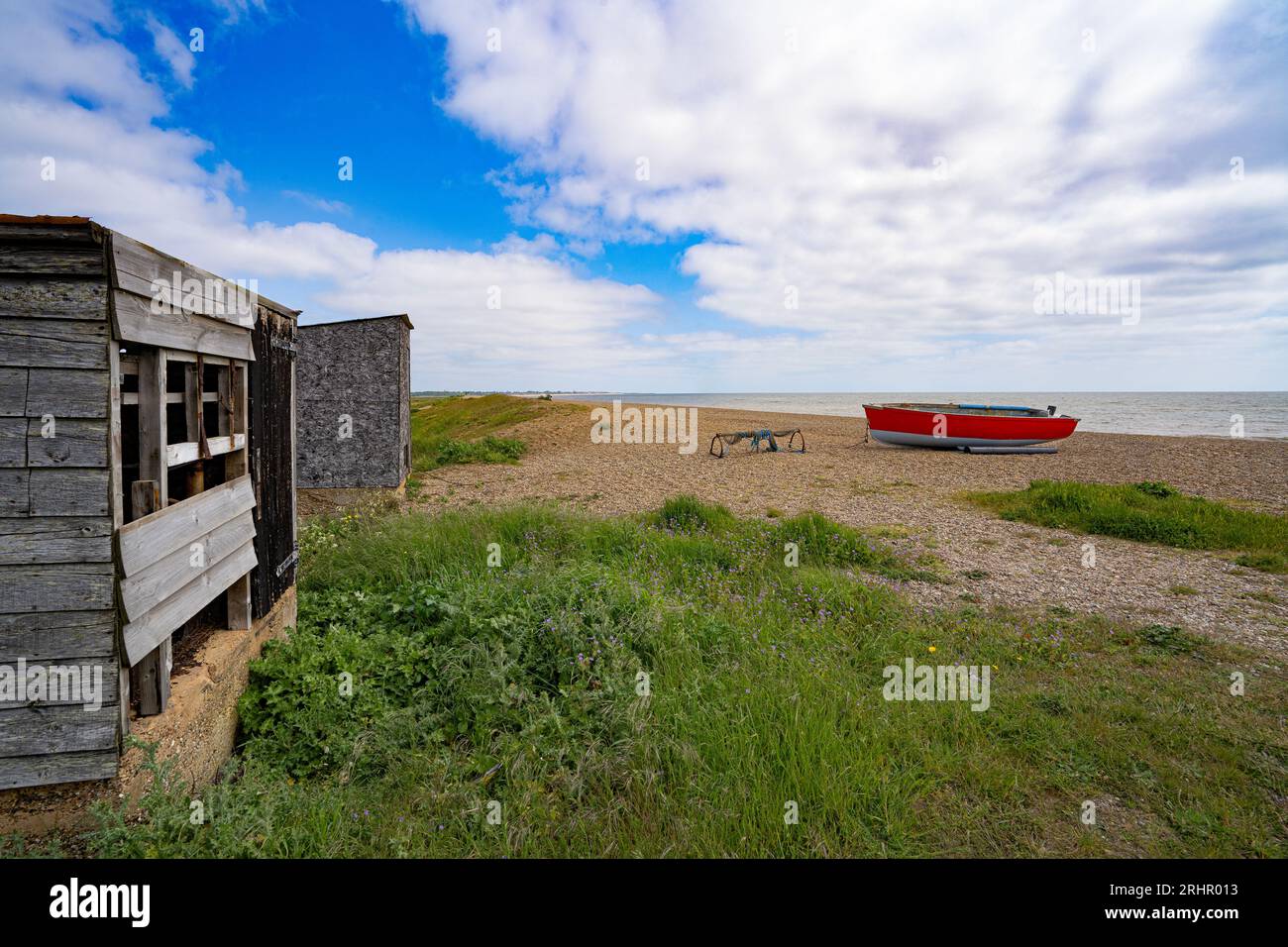 Capanne dei pescatori e barche sulla spiaggia di Dunwich, Suffolk, Inghilterra, Regno Unito Foto Stock