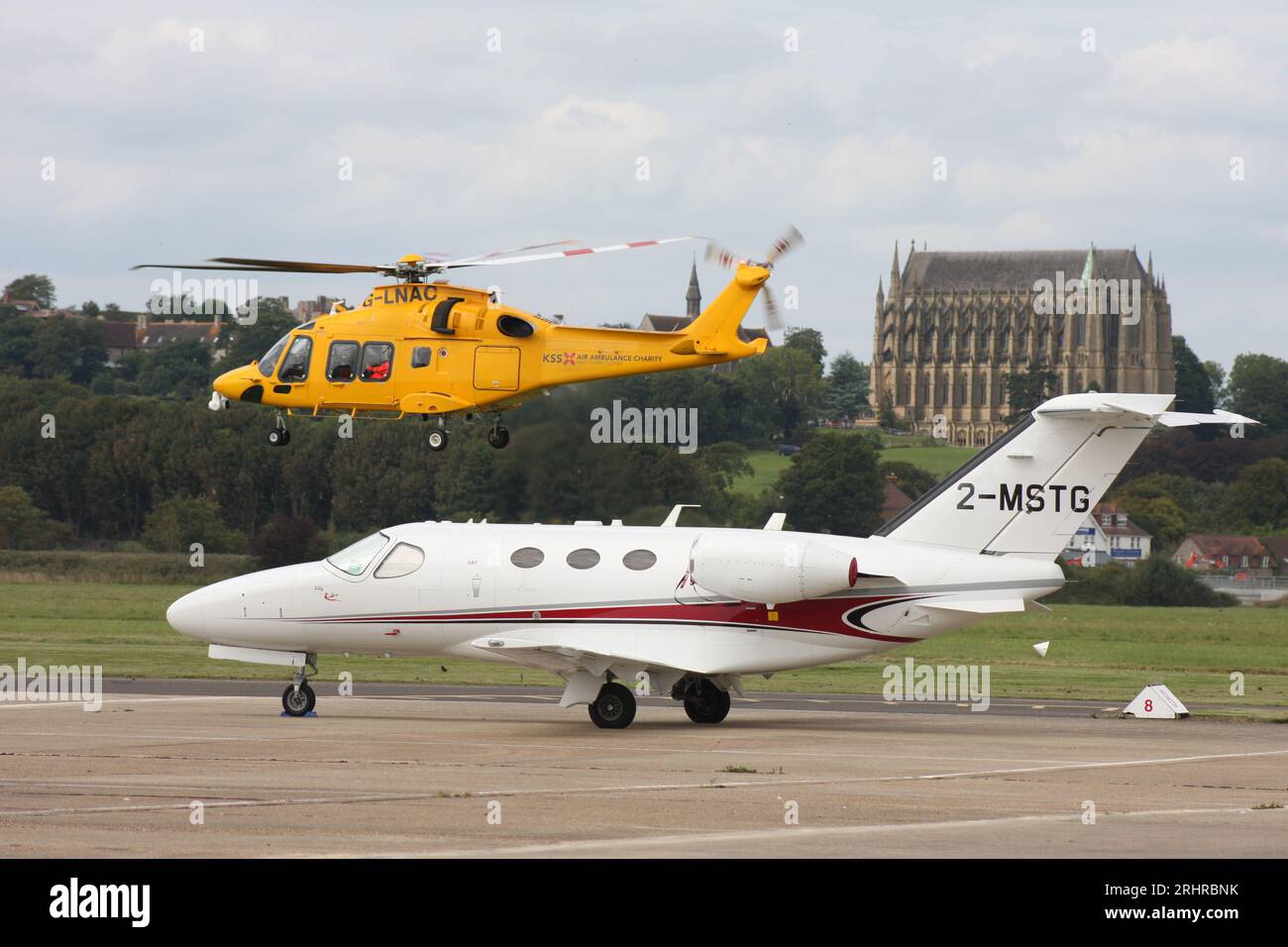 Un'ambulanza aerea AW-169 del Kent Surrey Sussex Trust parte dall'aeroporto di Brighton City con un business jet Cessna 510 Citation in primo piano. Foto Stock