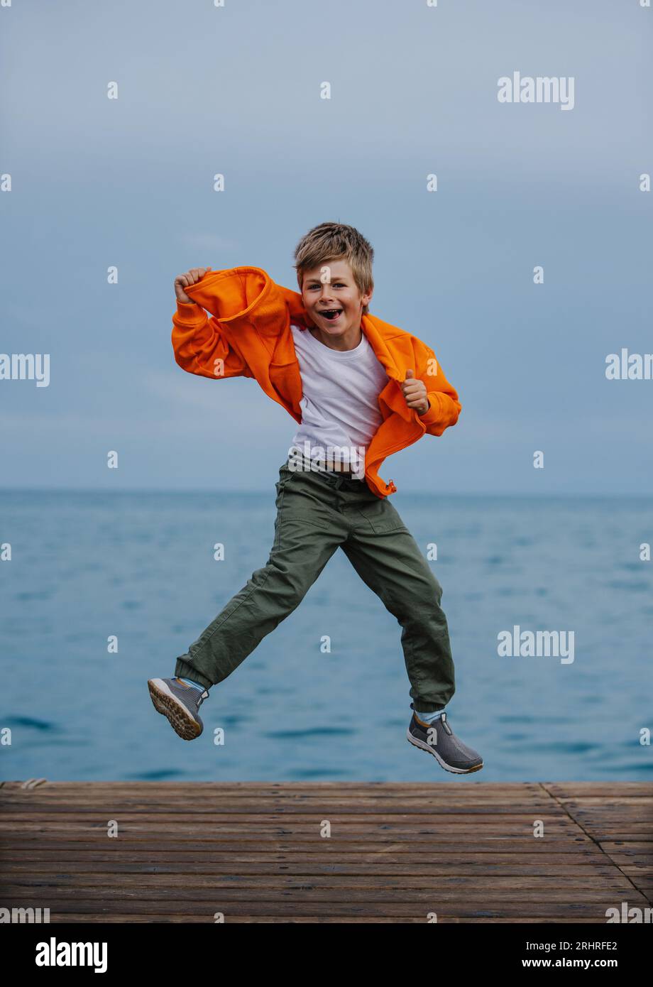 Felice ragazzo che salta in riva al mare Foto Stock