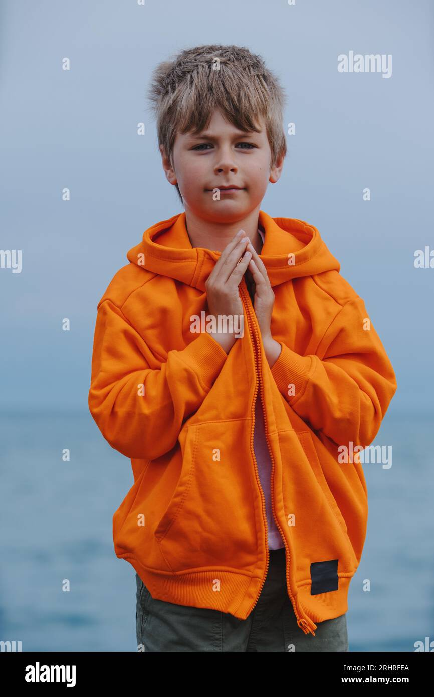 Ritratto di un ragazzo in piedi sulla riva del lago con le braccia piegate Foto Stock