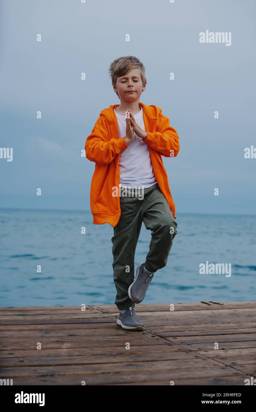 Un ragazzo in meditazione posa sul bordo del mare Foto Stock