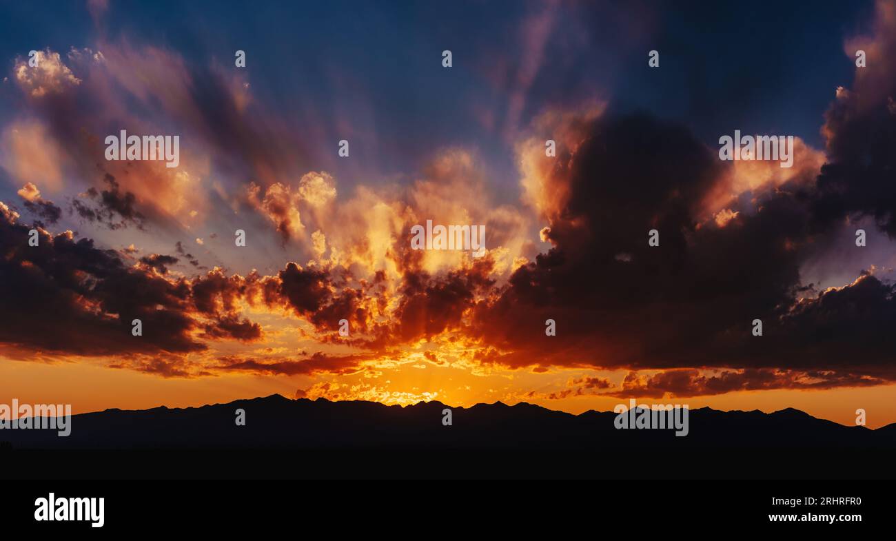 Rosso colorato cielo spettacolare alla luce del tramonto con silhouette di montagna Foto Stock