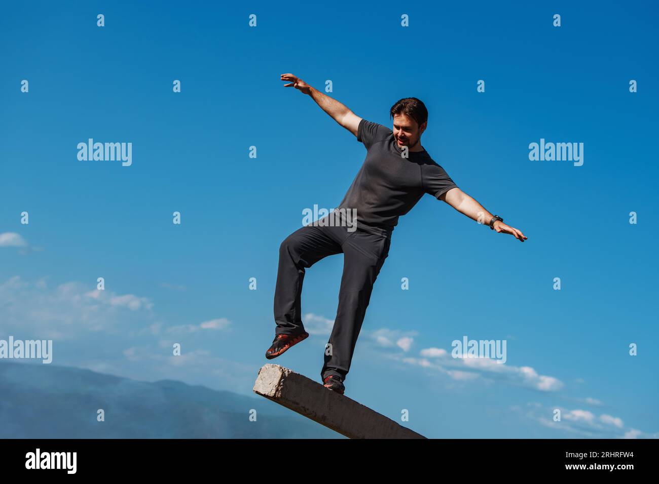 Giovane uomo che si trova in equilibrio su montagne Foto Stock