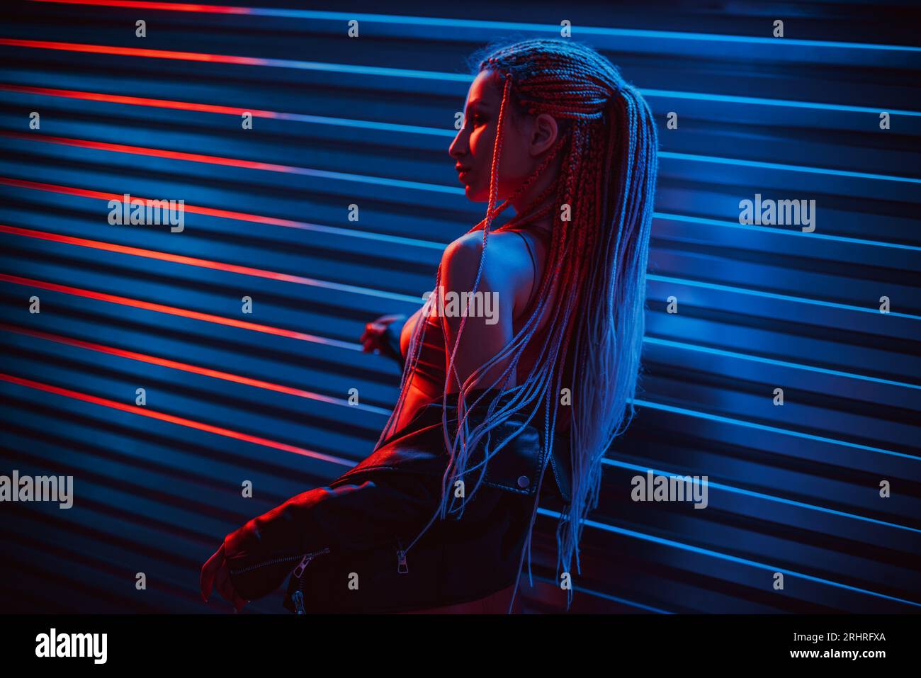 Giovane ballerina in posa all'interno di un night club buio con luci al neon Foto Stock