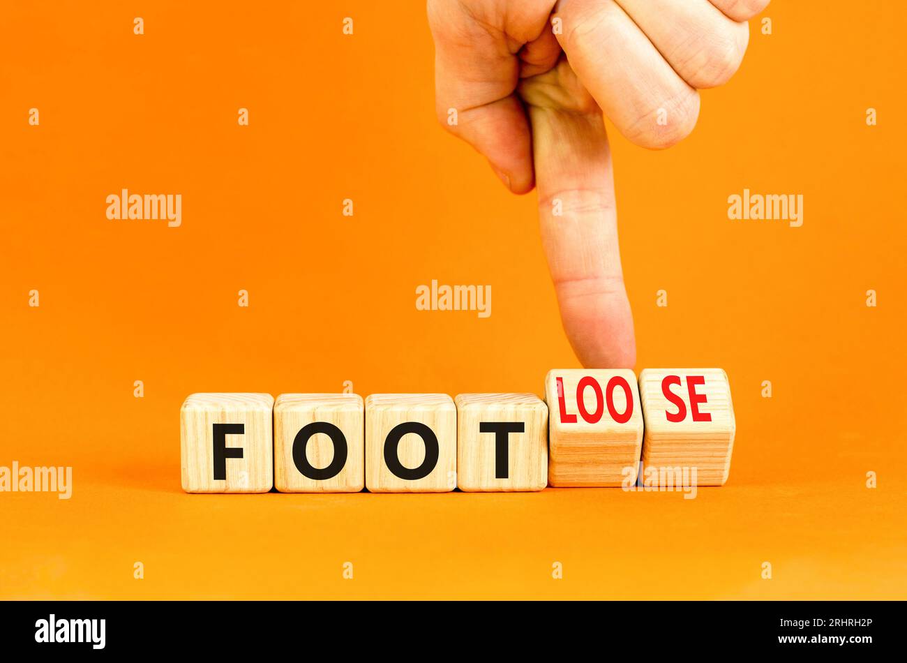 Simbolo piede o piede libero. Un uomo d'affari gira cubi di legno e cambia il nome di Footloose Footloose. Bellissimo sfondo arancione. Affari per Foto Stock