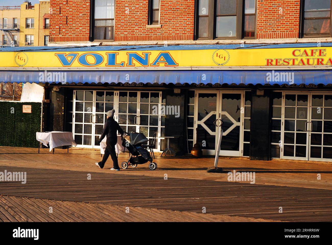 Una madre ruota un passeggino durante una giornata invernale sul lungomare di Brighton Beach, New York Foto Stock