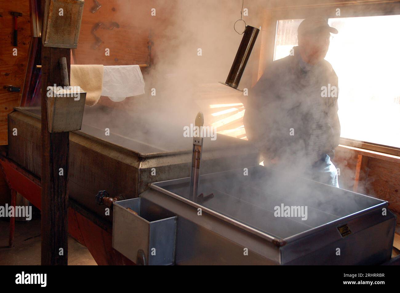 Un uomo adulto si trova nel vapore, creato dal processo di evaporazione nel fare lo sciroppo d'acero Foto Stock