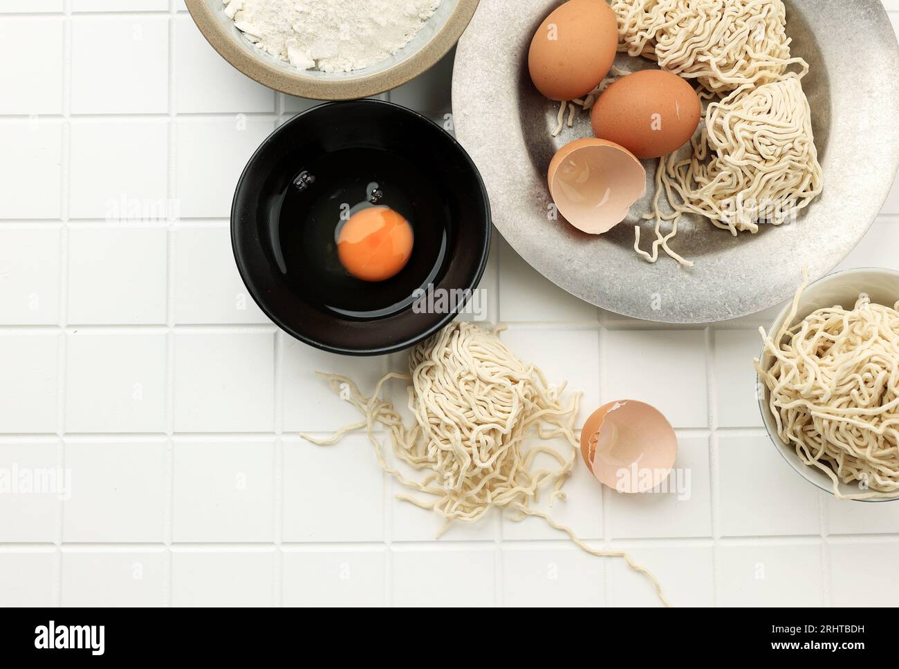Tagliatelle all'uovo crudo o mie Telur con vista dall'alto, tagliatelle fatte in casa in stile asiatico. Copia spazio per testo su tabella bianca Foto Stock