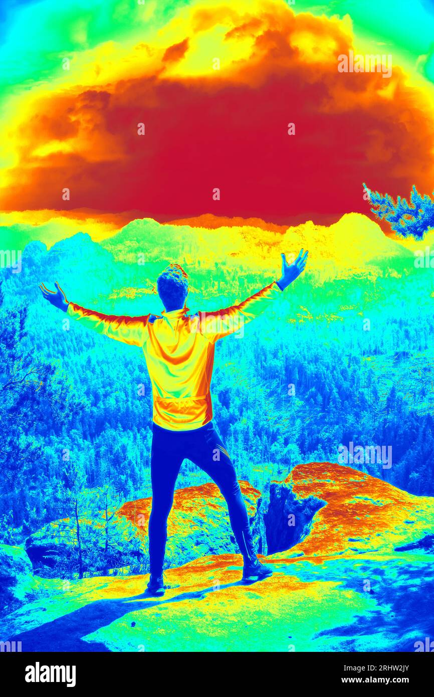 Uomo su una scogliera sopra la valle. I runner indossano tights e camicia gialla. Incredibile foto termografica del paesaggio. Foto Stock