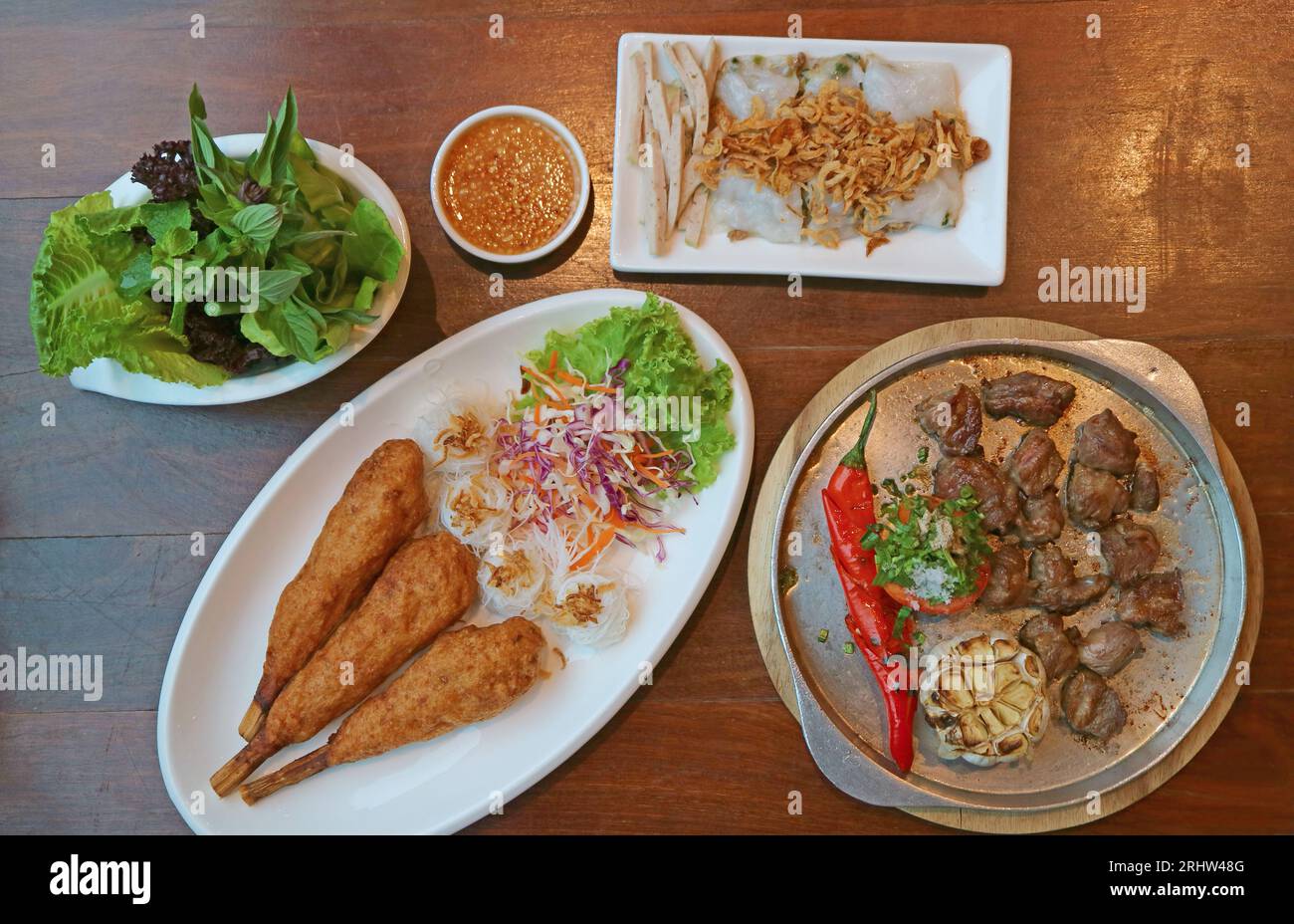 Deliziosi e popolari piatti vietnamiti serviti su un tavolo di legno Foto Stock