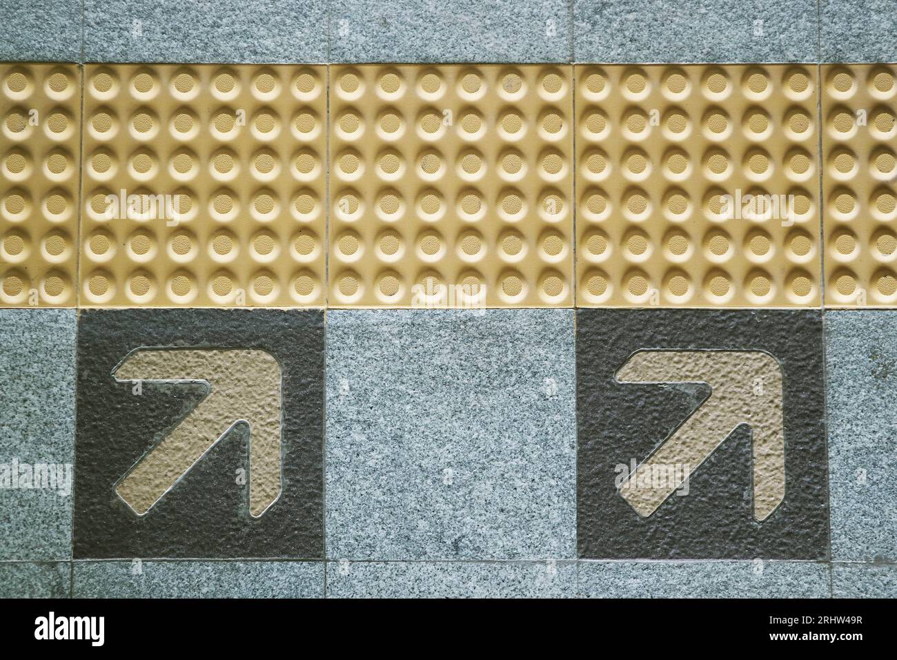 Pavimentazione tattile gialla e freccia della direzione di imbarco sulla piattaforma della metropolitana Foto Stock