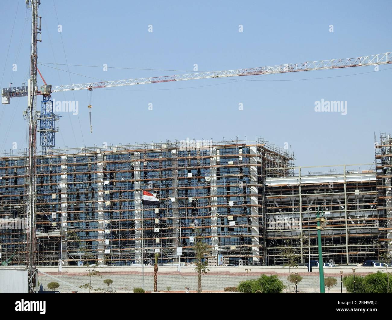 Cairo, Egitto, 21 luglio 2023: Un cantiere di un nuovo edificio industriale con ponteggi e gru di Hassan Allam Construction with the Waving Foto Stock