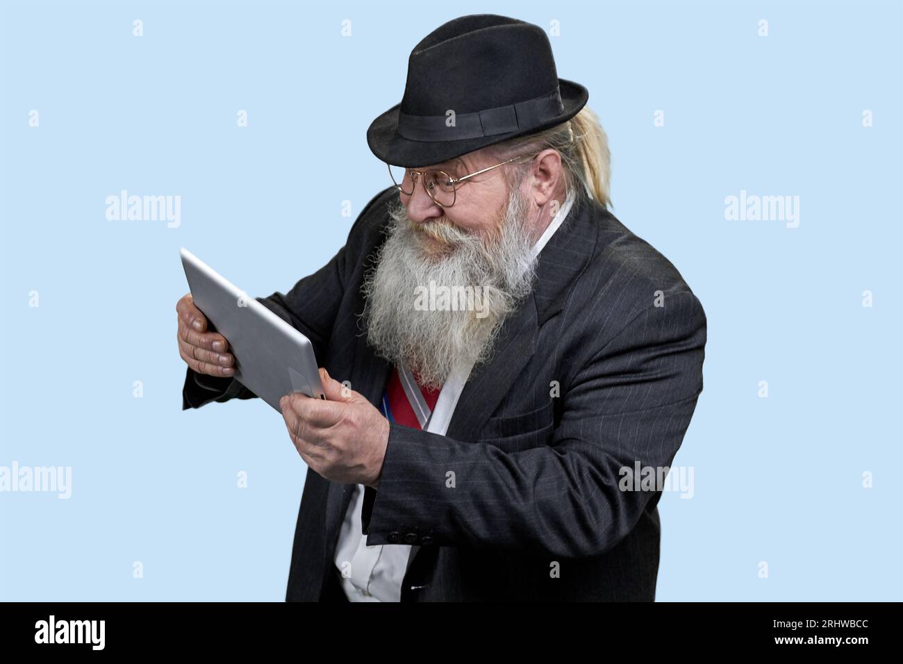Ritratto di un uomo anziano che gioca a videogame su un tablet pc. Isolato su blu. Foto Stock