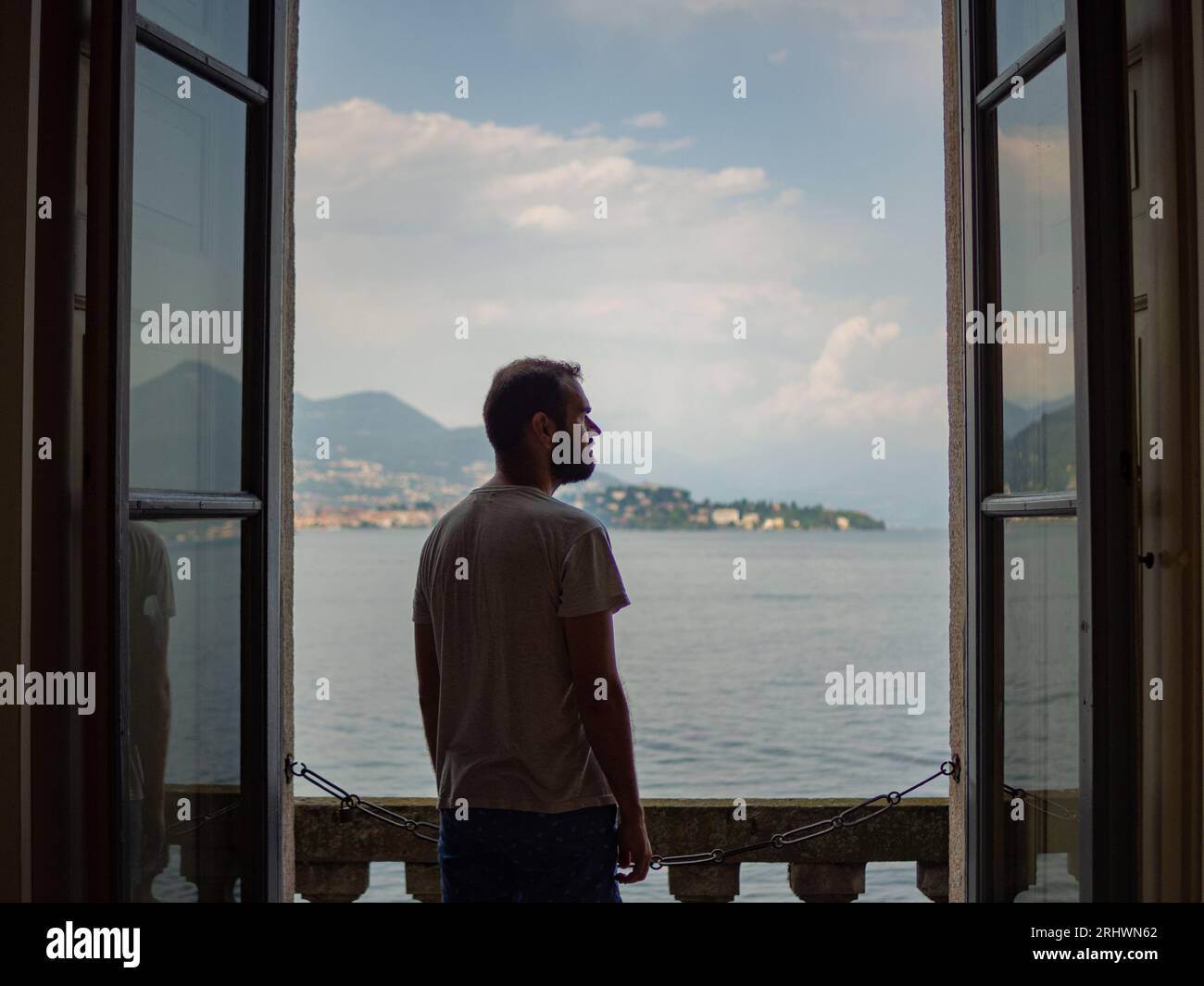 Giovane uomo che gode di una splendida vista di un palazzo a Stresa, in Italia, sull'isola bella. Foto Stock