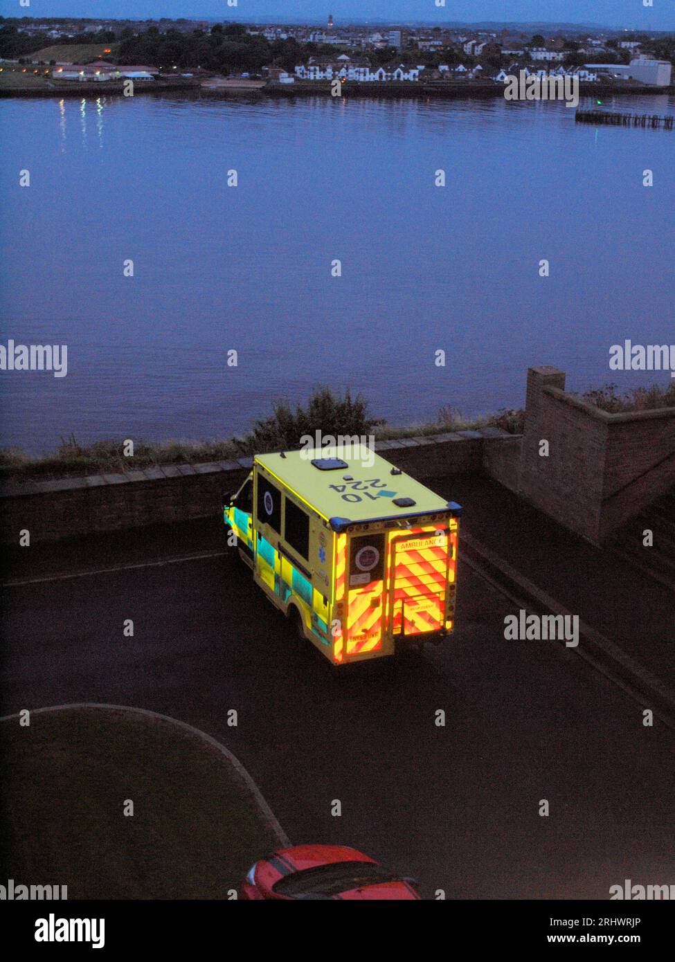 NHS 'Northumberland Ambulance Service' che assiste a una visita a casa in una zona pedonale nel nord del Tyneside in una calda serata estiva. Foto Stock