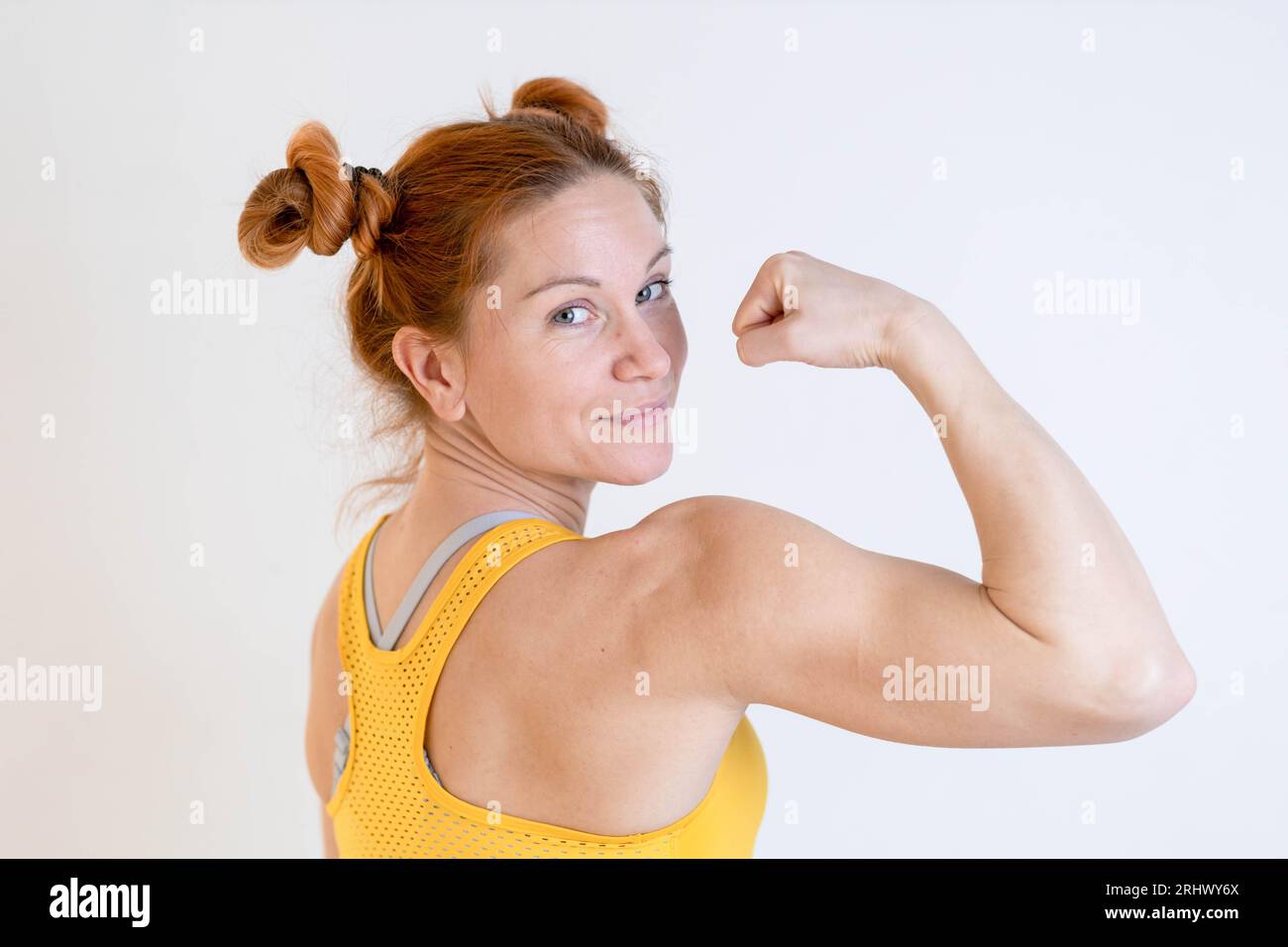 Donna giovane, bionda, in forma che mostra i suoi muscoli Foto Stock