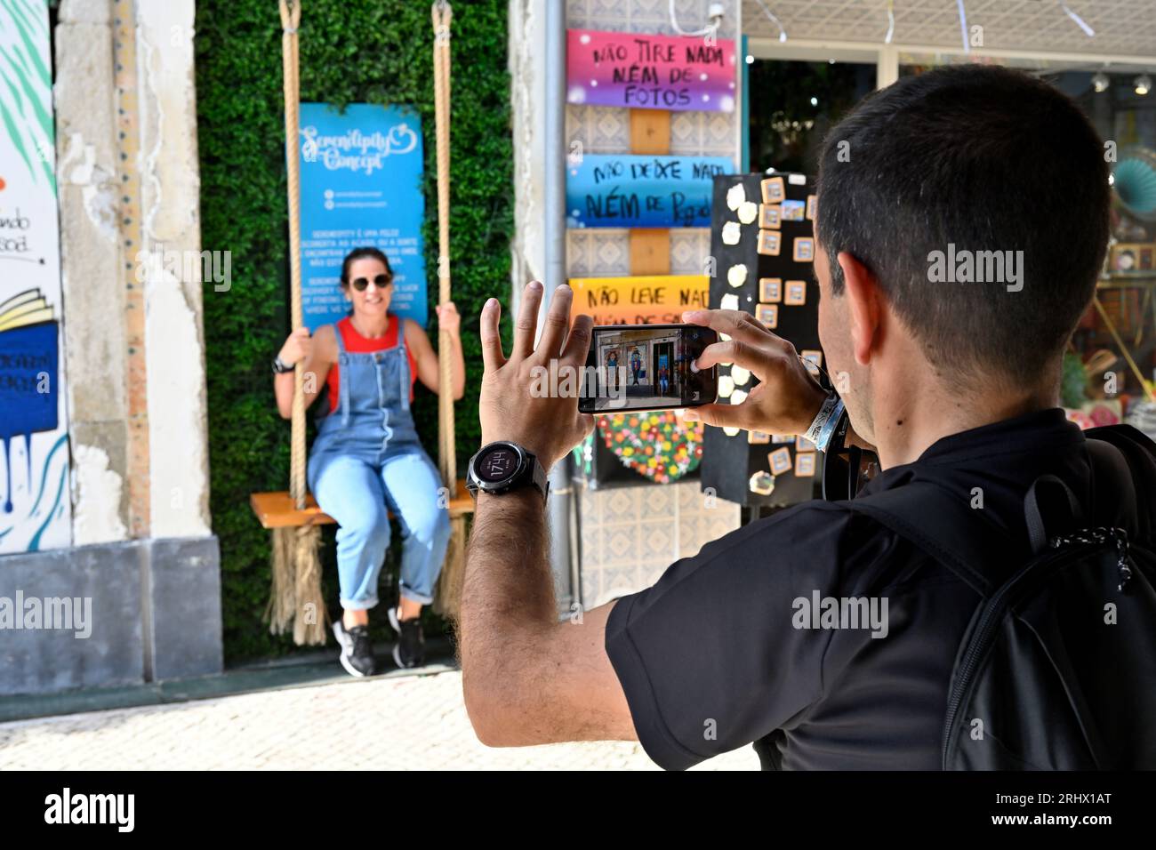 Piccolo e eccentrico spot con swing e Street art "Serendipity Concept" che attrae turisti, uomo che fotografa donna con il telefono Foto Stock