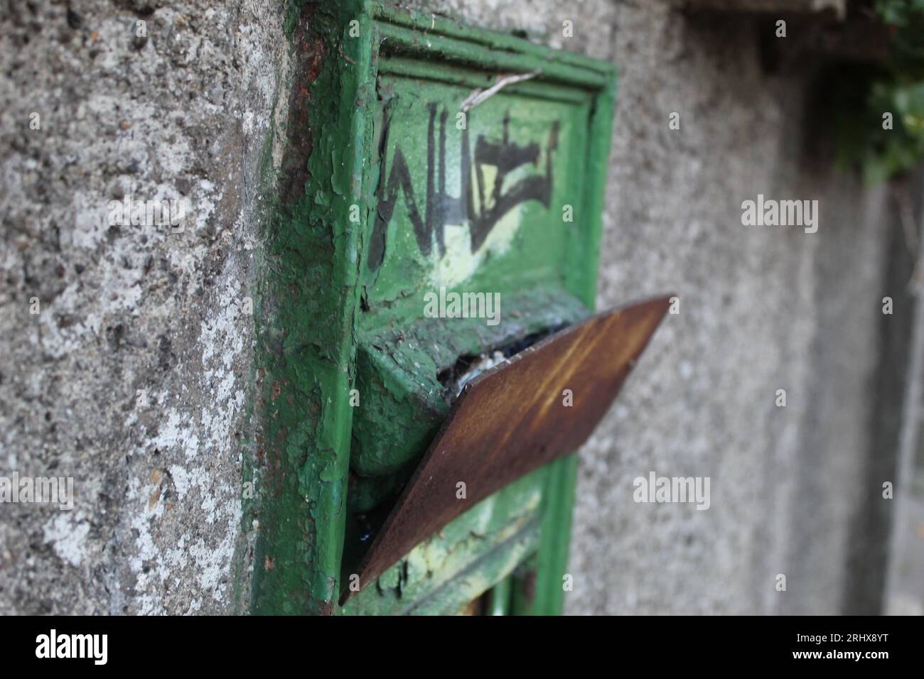 Una foto di una vecchia cassetta delle lettere verde su un muro di pietra. Foto Stock