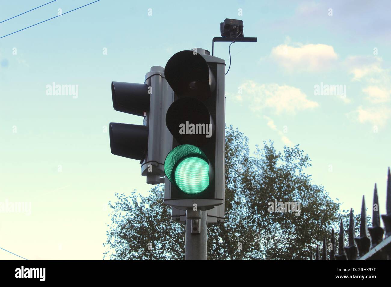 Una foto di un semaforo verde contro un cielo nuvoloso arancione. Foto Stock