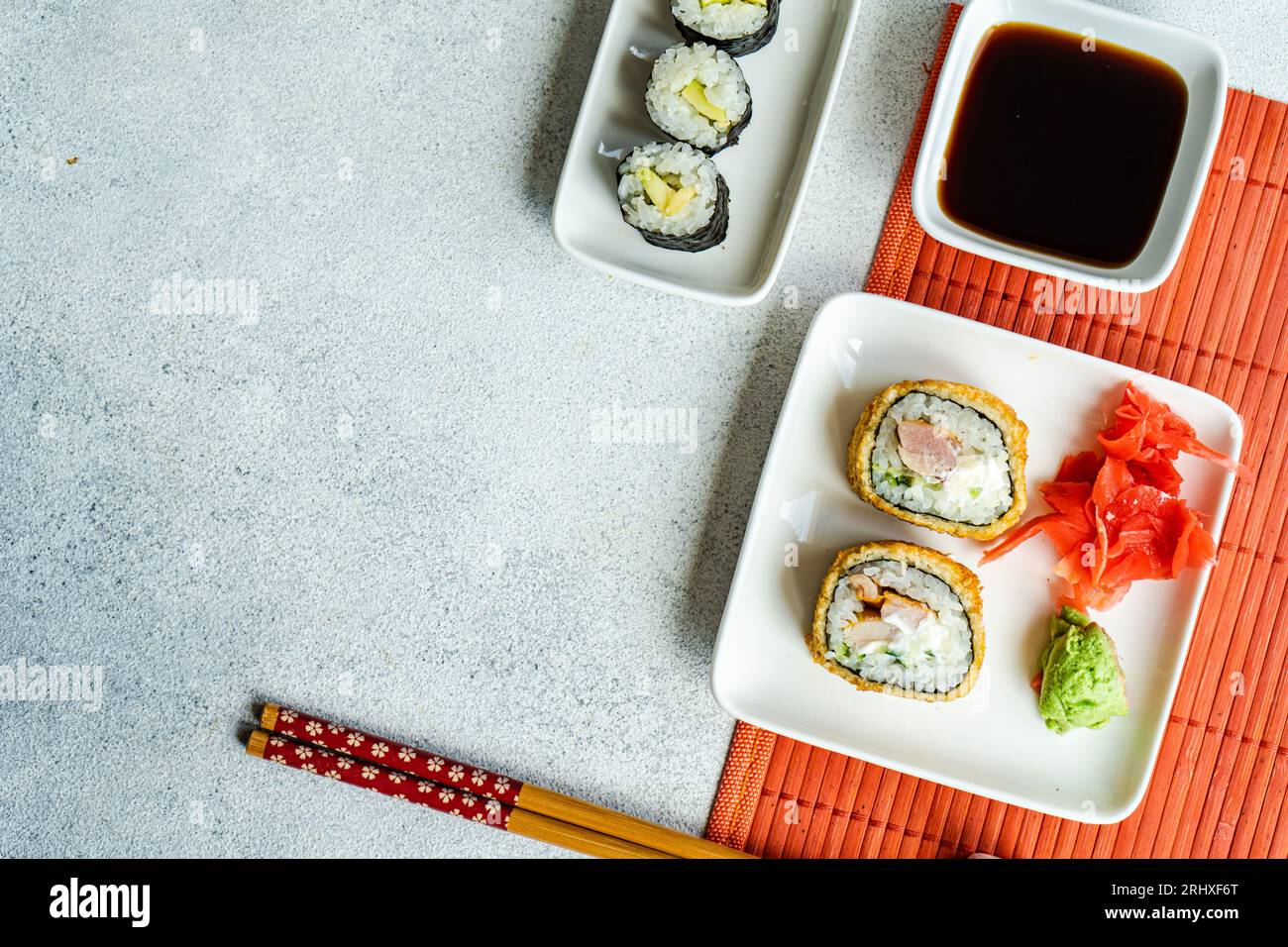 Dall'alto di vari panini di sushi su piatti con bacchette e salsa di soia su sfondo bianco Foto Stock