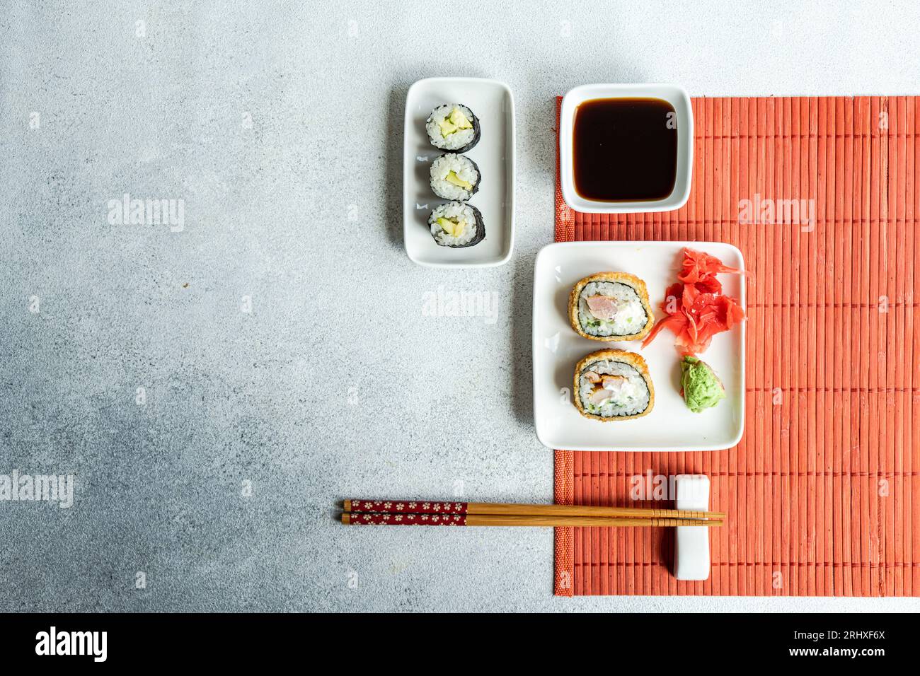 Dall'alto di vari panini di sushi su piatti con bacchette e salsa di soia su sfondo bianco Foto Stock