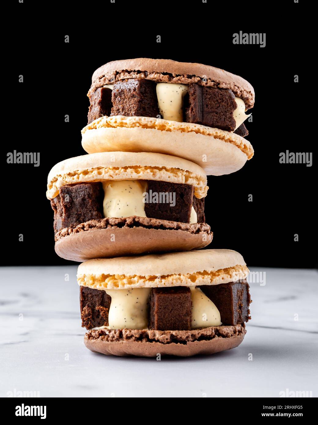 Brownie al cioccolato saporiti macaron su tavola in marmo e sfondo nero Foto Stock