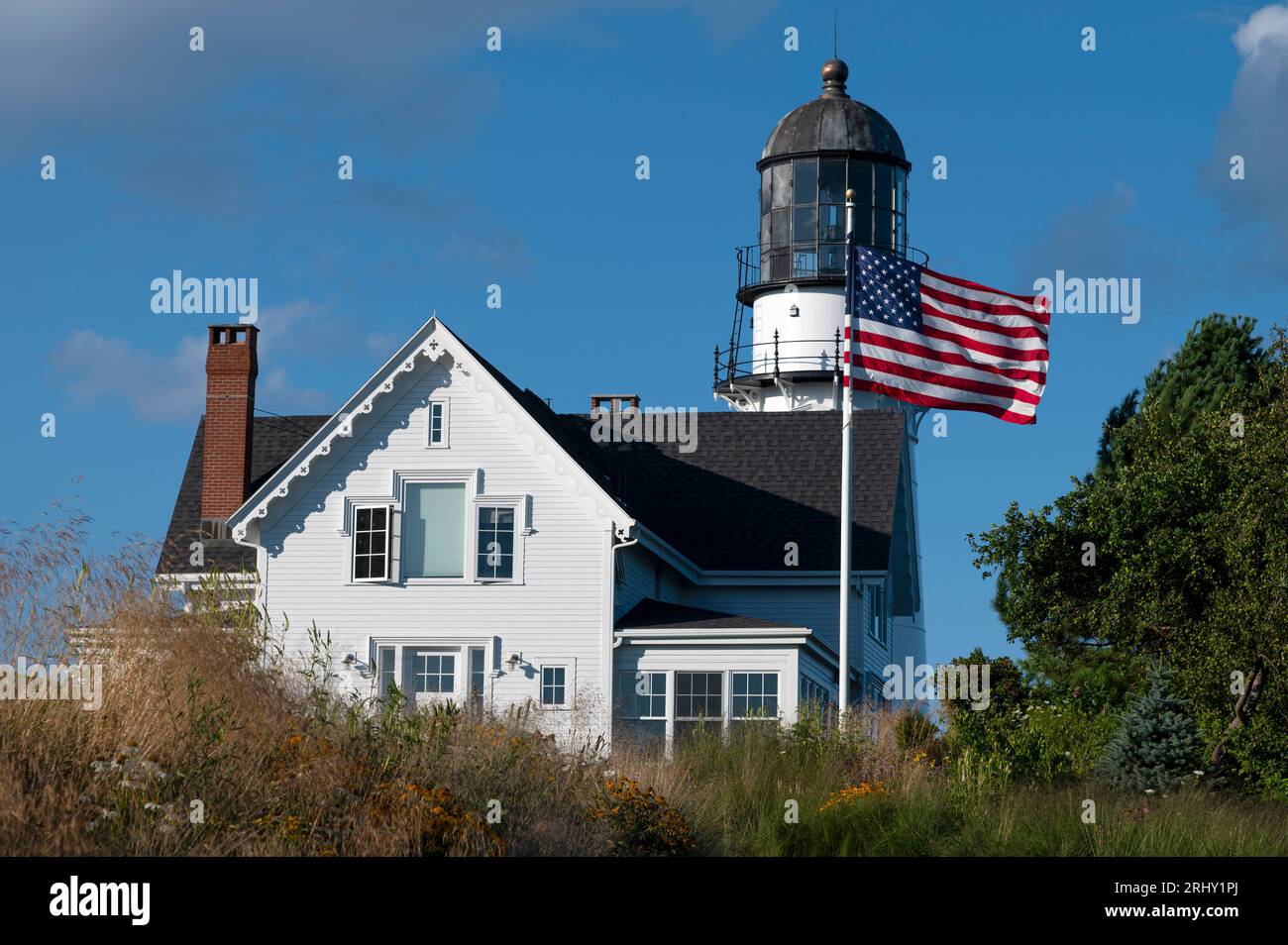 La bandiera americana ondeggia davanti al faro di Cape Elizabeth nel Maine in una ventosa giornata estiva. Foto Stock