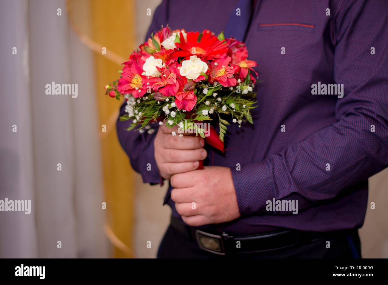 Un bouquet di fiori nelle mani di un uomo. Foto Stock