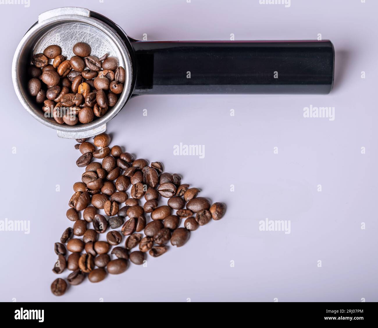 I chicchi di caffè sono in un braccio per la macchina da caffè e su un tavolo bianco Foto Stock