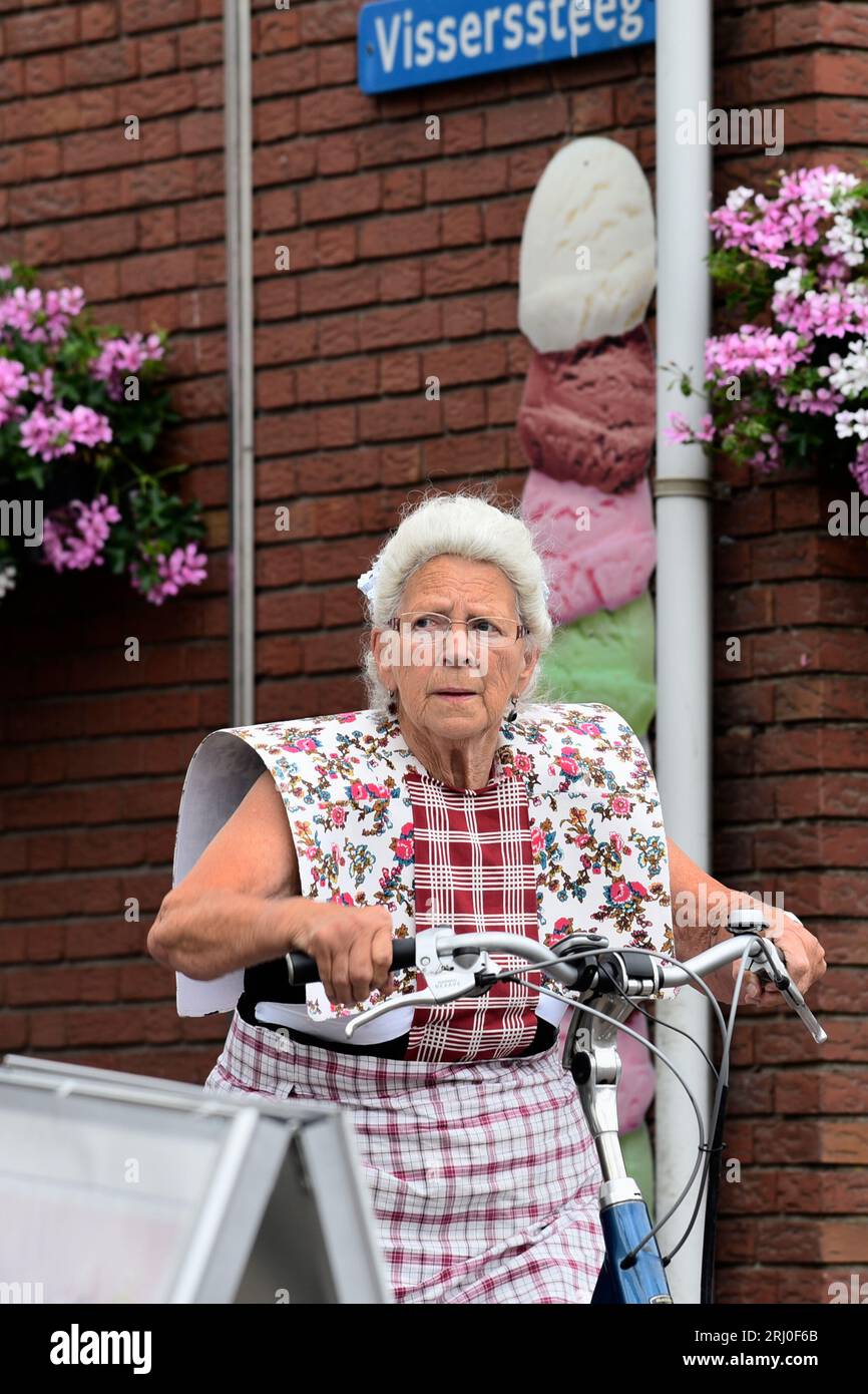 Donna con bicicletta nel tipico costume del villaggio di Spakenburg, Paesi Bassi Foto Stock