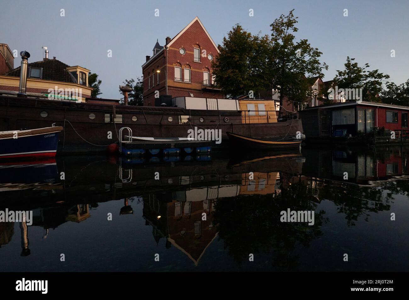 Barche tradizionali olandesi attraccate lungo il fiume nel centro della città di Haarlem Foto Stock