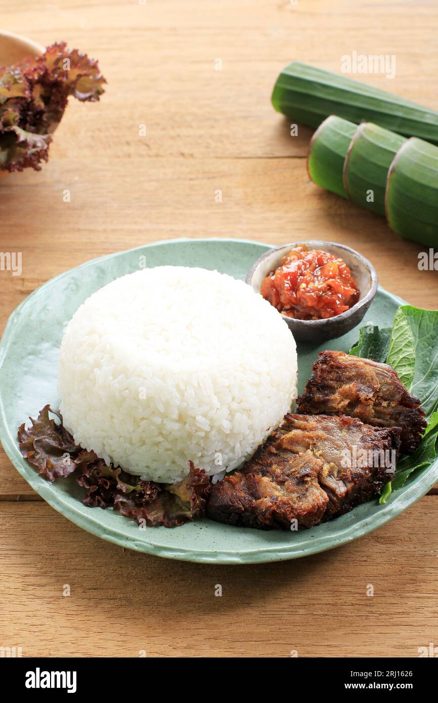 Nasi Empal Goreng, carne fritta giavanese servita con riso bianco al vapore. Servita su un tavolo di legno Foto Stock