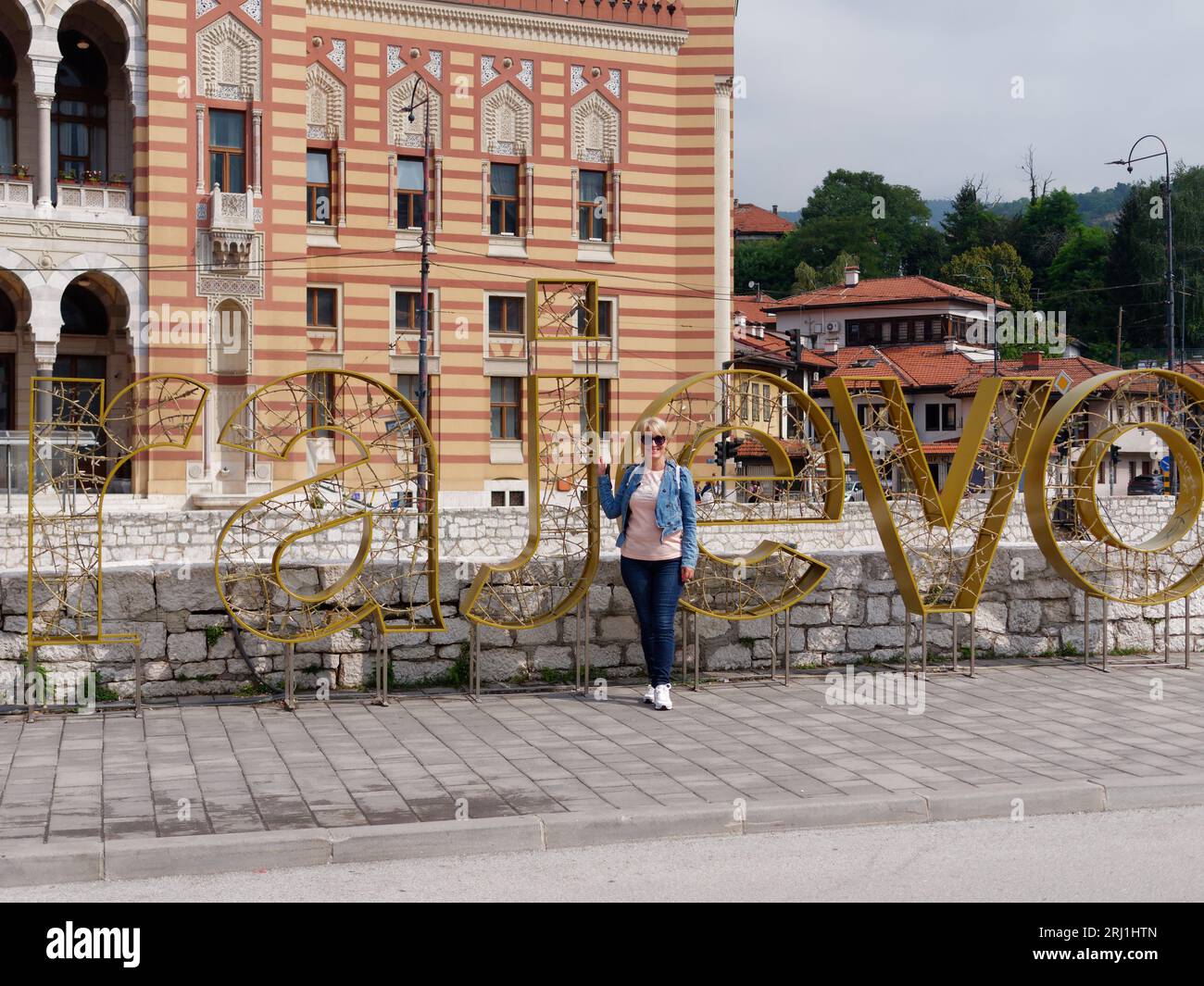 Il turista si trova accanto al cartello Sarajevo di fronte al municipio nella città di Sarajevo, Bosnia ed Erzegovina, 19 agosto 2023. Foto Stock