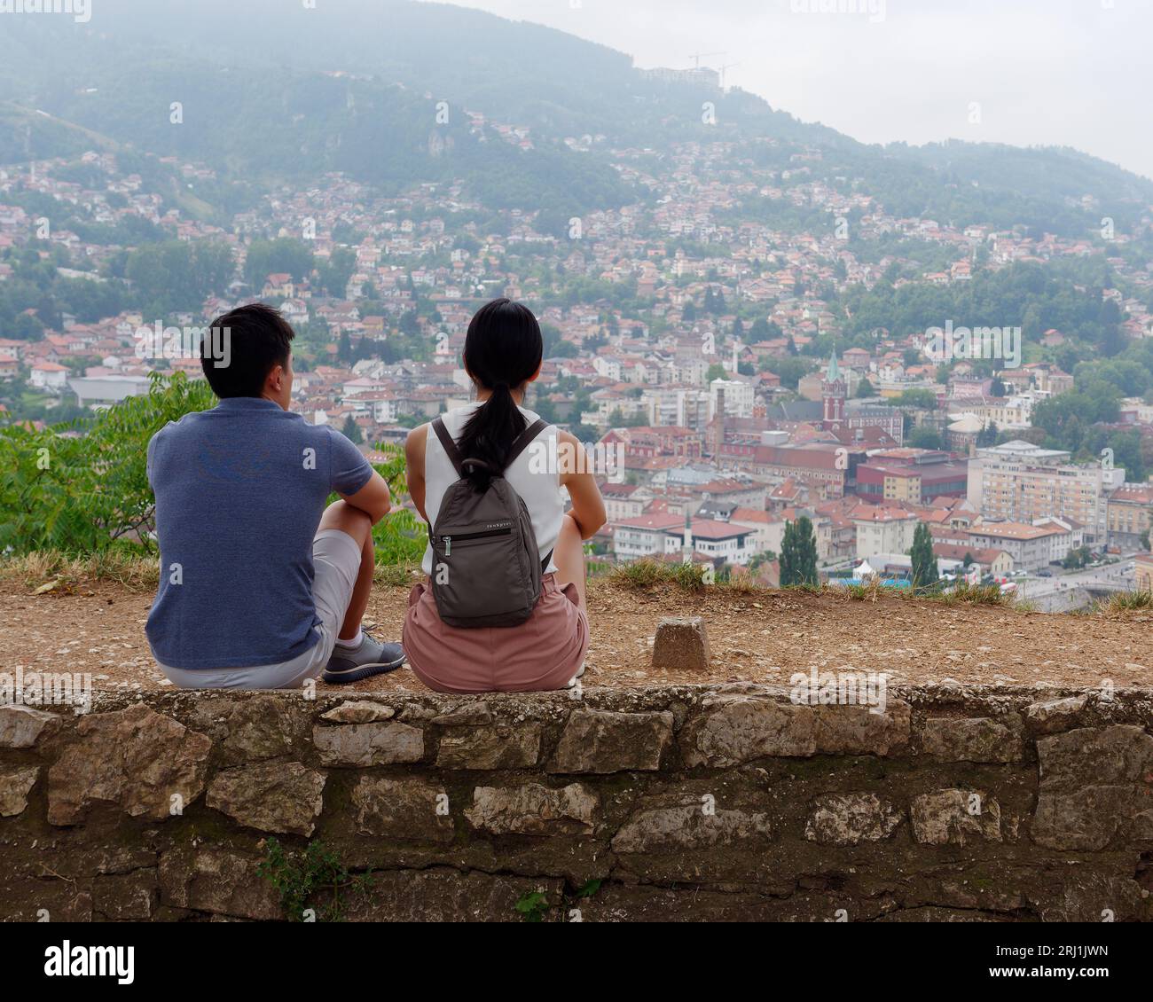 La coppia si siede su un muro godendo della vista dalla Fortezza gialla sulla città di Sarajevo, Bosnia ed Erzegovina, 19 agosto 2023. Foto Stock