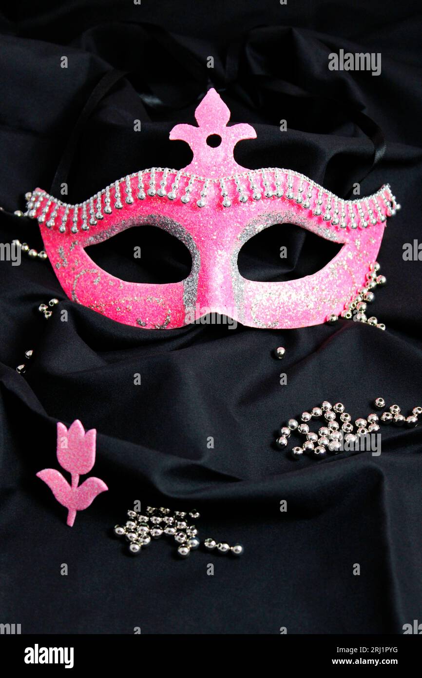 Maschera glitterata rosa sul buio Foto Stock