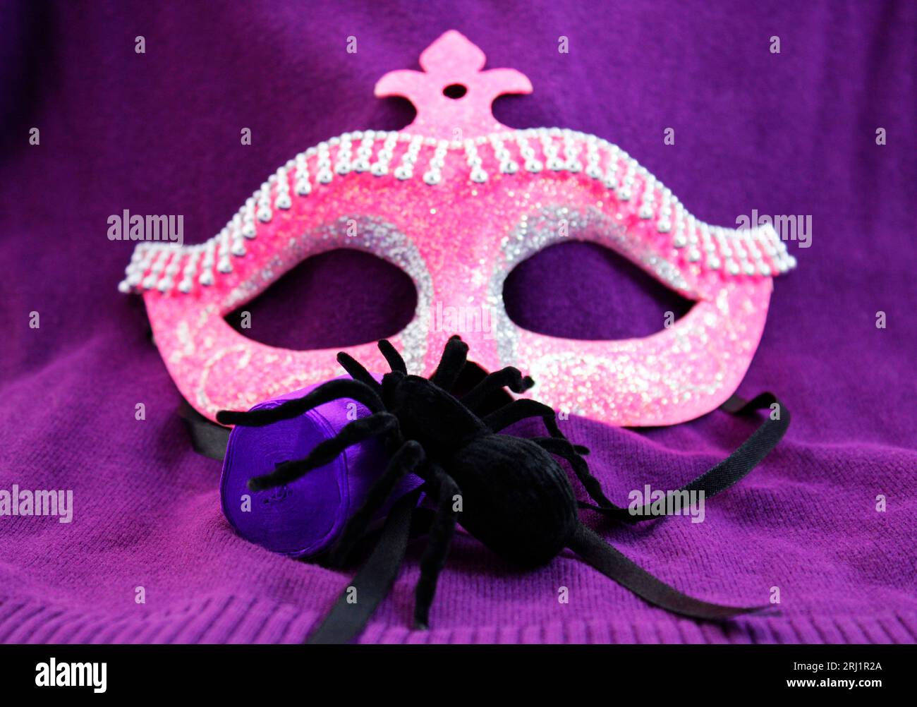Maschera glitterata rosa e ragno su sfondo scuro Foto Stock