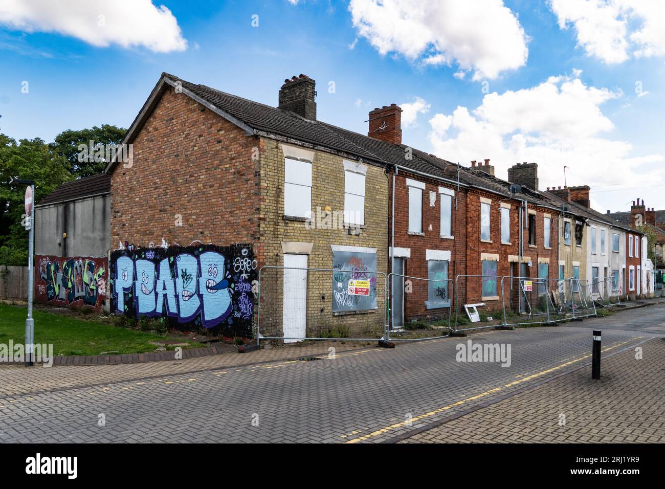 Una fila di case a terrazze bruciate e abbandonate nel nord dell'Inghilterra con finestre, porte e tetti danneggiati dal fuoco in attesa di demolire e. Foto Stock
