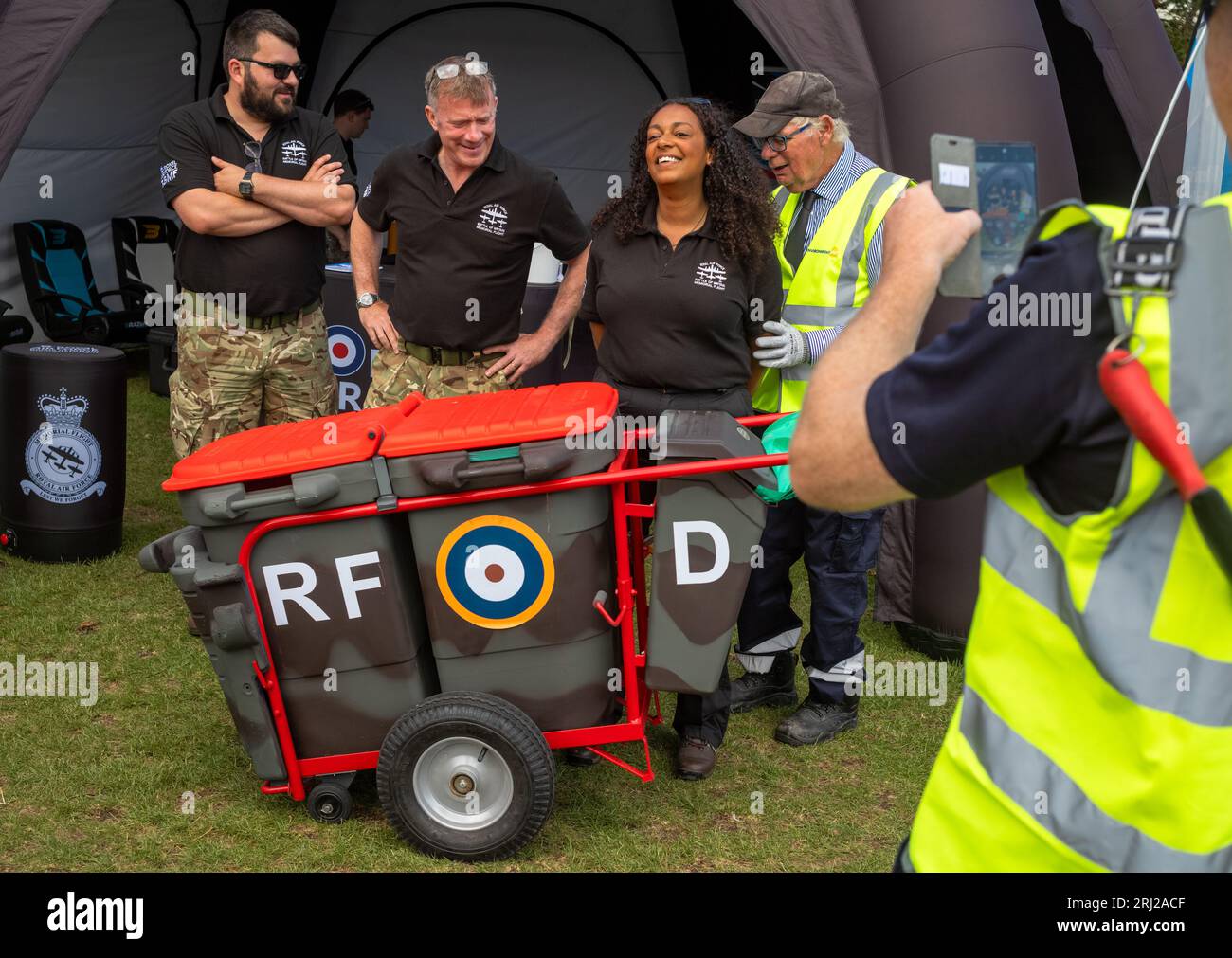 Un anziano cestino municipale con i suoi bidoni dipinti nei colori del mimetismo militare e con una rosa della RAF posa una foto con un membro del team di supporto Foto Stock