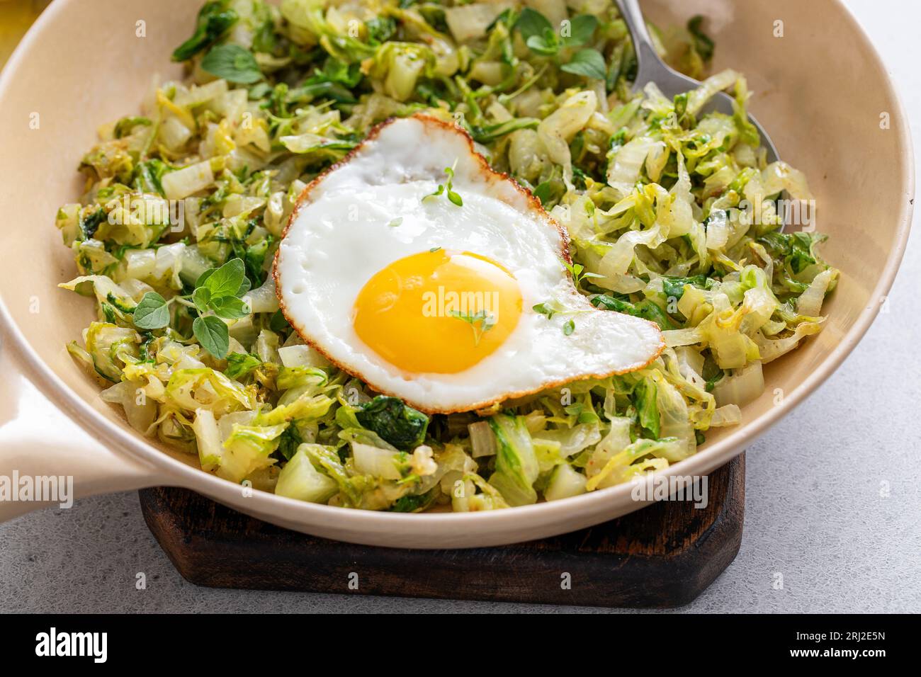 Cavolo saltato con uovo fritto in una padella di ghisa, un'idea salutare per il pranzo con verdure Foto Stock