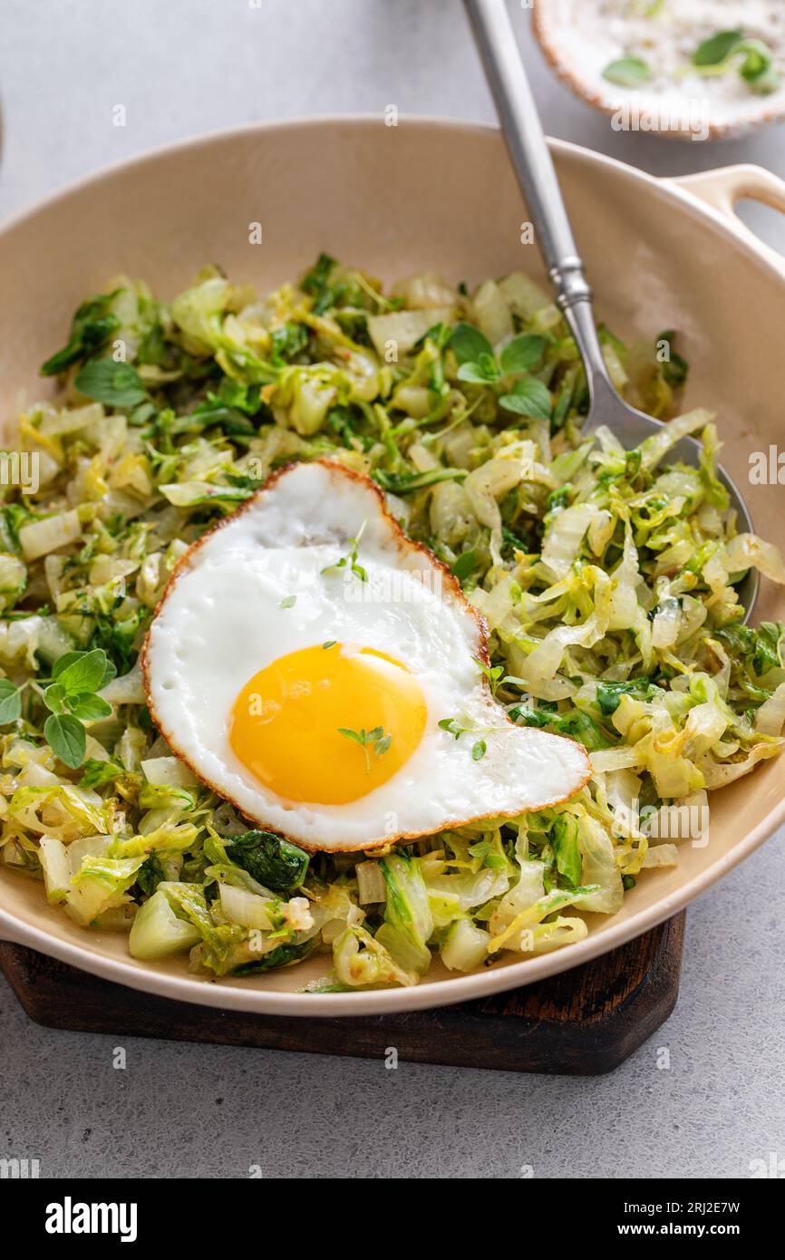 Cavolo saltato con uovo fritto in una padella di ghisa, un'idea salutare per il pranzo con verdure Foto Stock