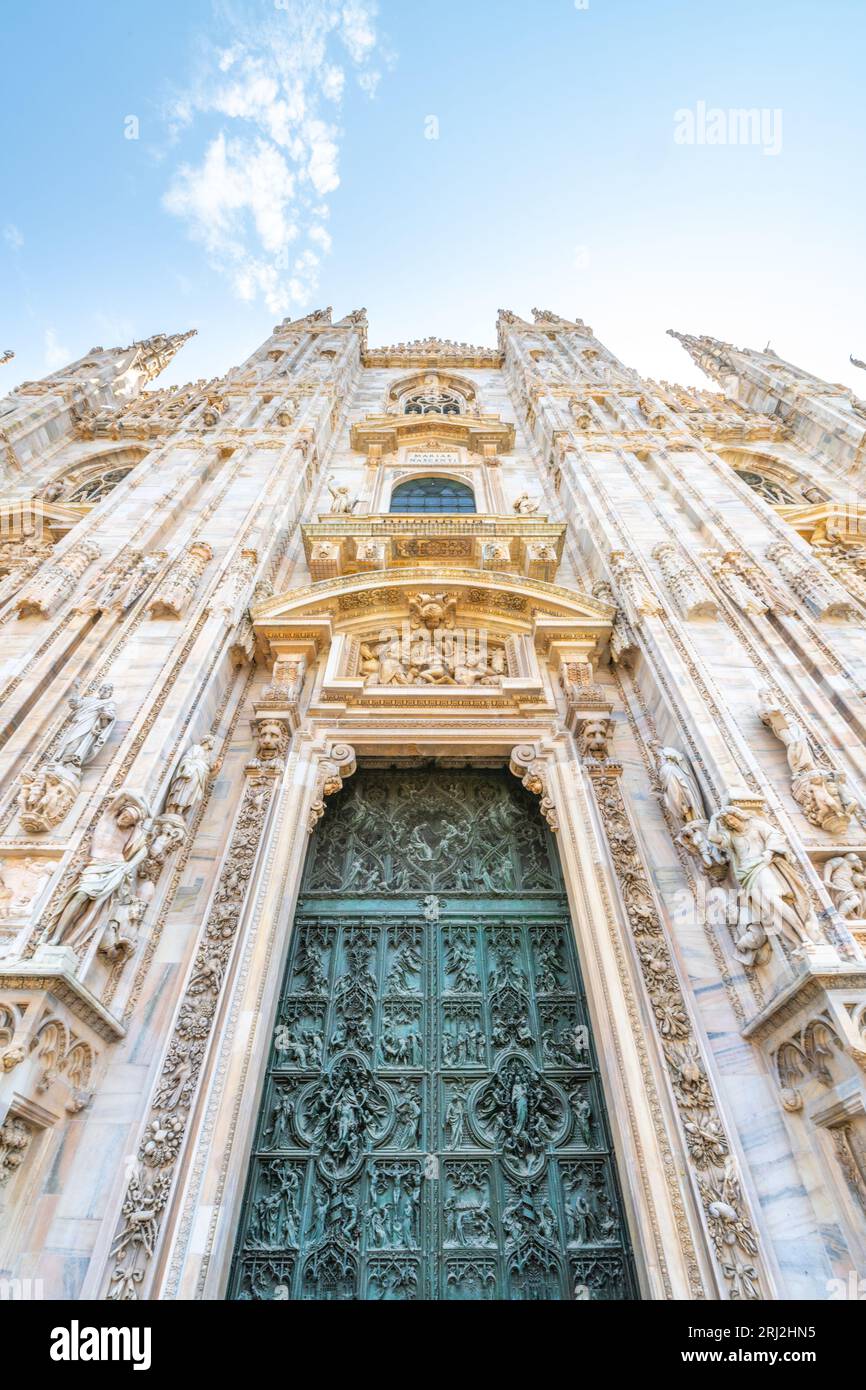Cattedrale di Milano, in italiano: Duomo di Milano o Cattedrale metropolitana-Basilica della Natività di Santa Maria. Vista della porta principale e della facciata in marmo bianco nelle soleggiate giornate estive. Milano, Lombardia, Italia Foto Stock