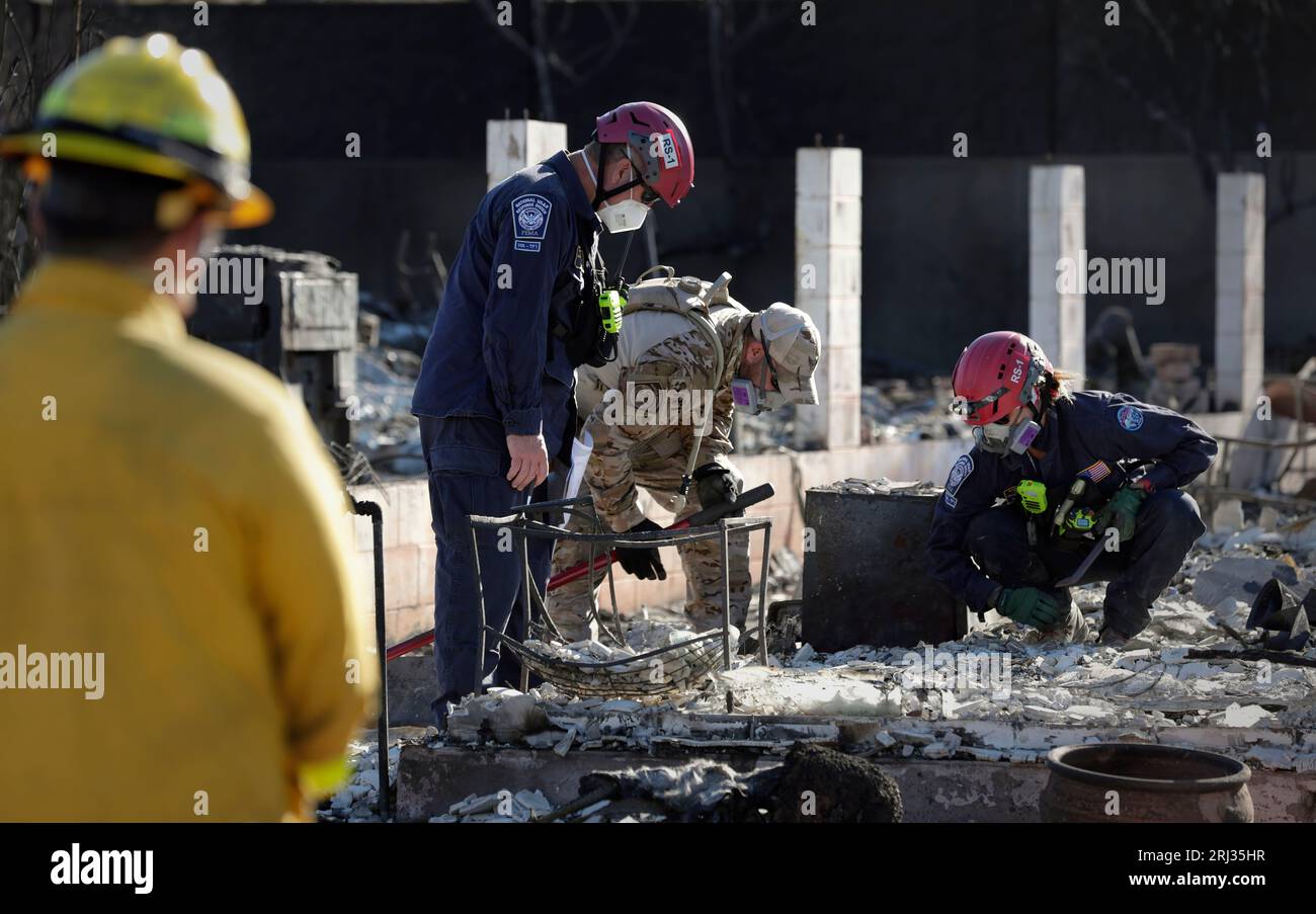 I membri del team Urban Search and Rescue della Federal Emergency Management Agency e un agente di pattuglia di frontiera degli Stati Uniti, il centro, guardano da vicino mentre attraversano un quartiere distrutto da un incendio a Lahaina, Hawaii, 17 agosto 2023. Foto del CBP di Glenn Fawcett Foto Stock